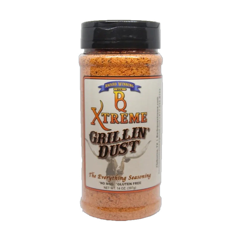 Bottle of B Xtreme BBQ Grillin Dust beside grilled steak, ribs, and corn on a wooden board