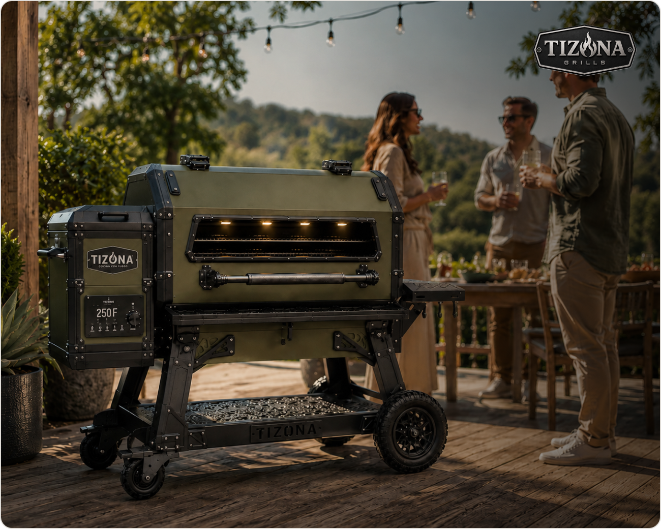 A Tizona kamado grill glowing at dusk on a wooden patio while friends gather around a table strung with lights