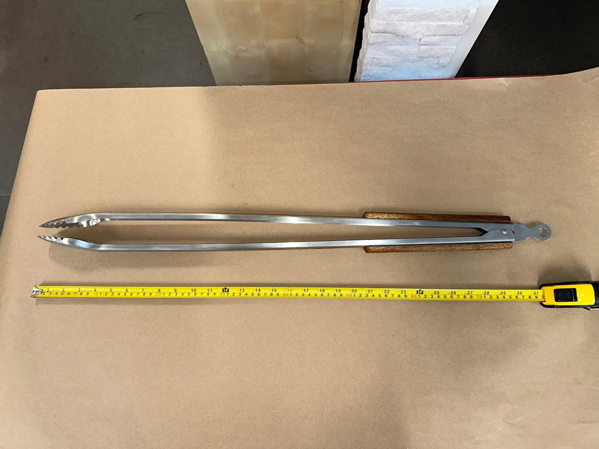32 inch stainless steel campfire tongs with wood handle next to a tape measure